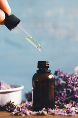 Bottle with aroma oil and lavender flowers on blue background - obrazy, fototapety, plakaty