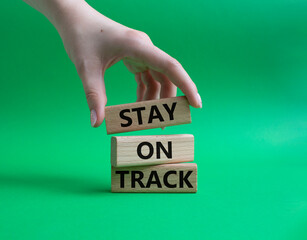 Stay on track symbol. Wooden blocks with words Stay on track. Beautiful green background. Businessman hand. Business and Stay on track concept. Copy space.