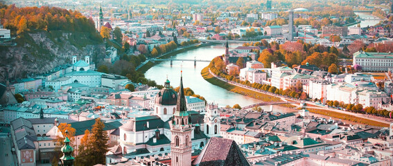 Naklejka premium Banner travel with panoramic view in a Autumn season at a historic city of Salzburg with Salzach river in beautiful golden evening light sky and colorful of autumn at sunset, Salzburger Land, Austria