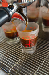 Espresso from a coffee machine pouring into a white cup of coffee.