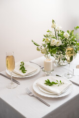 Wedding teble decoration with white flowers, glasses and white napkins. Elegantly decorated table at a wedding reception. Festive table setting. The wedding decor.