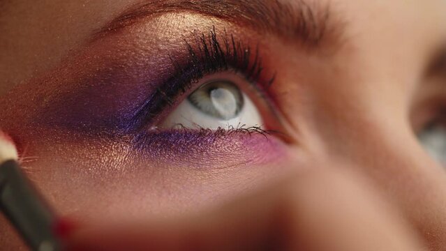 Make-up artist applies makeup to the upper eyelid, close-up.  Makeup artist applies a bright eye shadow with a makeup brush.Tutorial master class of professional makeup. Slow motion cinematic shoot.