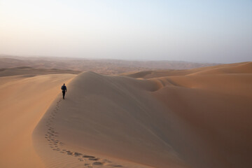 Fototapeta na wymiar Man with a camera and backpack in desert at sunrise.