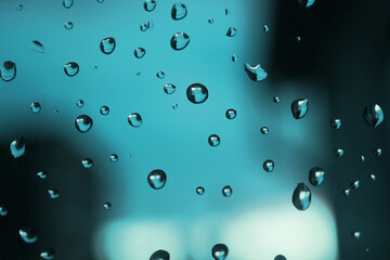 Raindrops on window glass. Turquoise tinted background. Abstract natural backdrop. After the rain. Macro