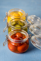 Homemade Pickles Canned Food Cucumbers Cherry Tomatoes and Small Yellow Squash on Blue Background Above Vertical