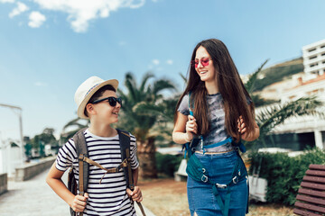 Brother and sister walking together at seaside with luggage backpack. Travel, tourism,  family concept.