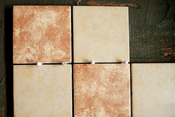 A section of freshly laid brown and cream tiles on the wall with plastic gaskets. Repair work