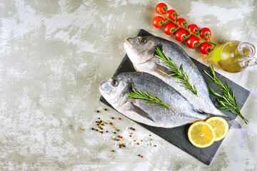 Fresh fish dorado and ingredients for cooking. Raw fish dorada with spices and herbs on gray concrete table. Seafood, restaurant, diet, healthy food background. Top view, flat lay with copy space