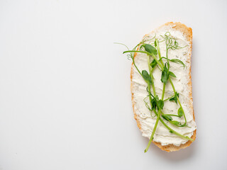Close-up of a slice of bread spread with cottage cheese and decorated with micro greenery isolated...