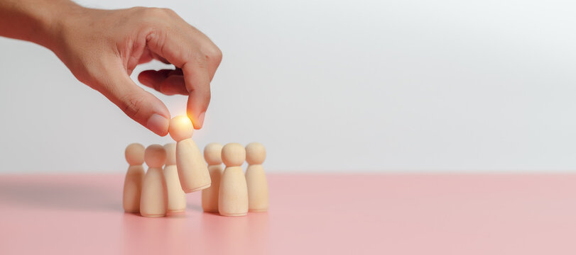 Leadership of teamwork concept. Wooden figures human was chosen leadership of teamwork. man's hands are select wooden puppet to devise strategies for appointing leaders.