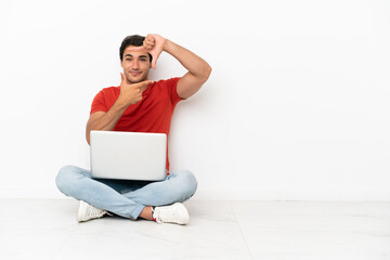 Caucasian handsome man with a laptop sitting on the floor focusing face. Framing symbol