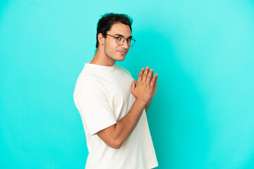 Caucasian handsome man over isolated blue background scheming something