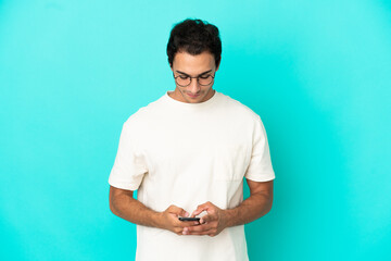 Caucasian handsome man over isolated blue background sending a message with the mobile