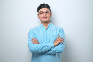 Asian man standing with arms crossed and smiling at camera isolated over white background - obrazy, fototapety, plakaty