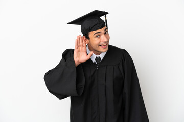 Young university graduate over isolated white background listening to something by putting hand on the ear