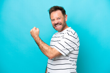 Middle age caucasian man isolated on blue background celebrating a victory