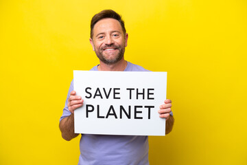 Middle age caucasian man isolated on yellow background holding a placard with text Save the Planet with happy expression