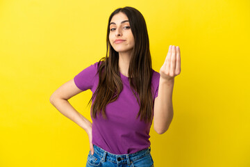 Young caucasian woman isolated on yellow background making Italian gesture