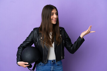 Young caucasian woman with a motorcycle helmet isolated on purple background extending hands to the side for inviting to come