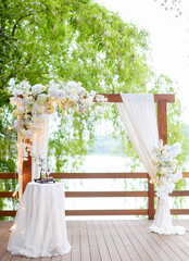 Beautiful summer wedding arch for ceremonies in the forest against the background of the lake