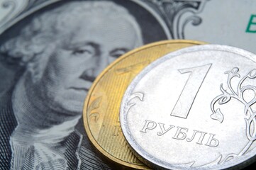 a coin with a face value of 1 ruble lies on a banknote of the American dollar. close-up