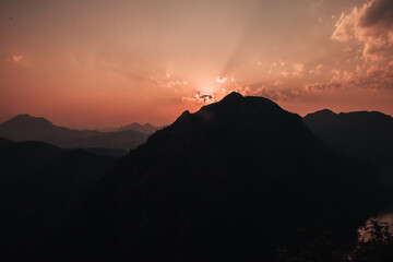  colorful sunset over the mountains in Nong Khiaw with clouds in the sky over the village and the Nam Ou river