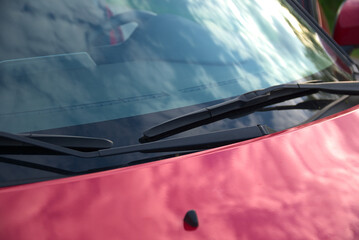 Car windshield wipers on the windshield of the car. Body elements. Red car body. - obrazy, fototapety, plakaty
