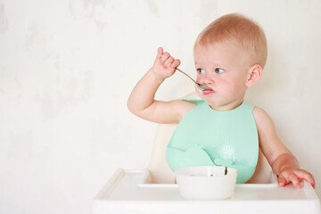 kid eats with a spoon and learns by himself