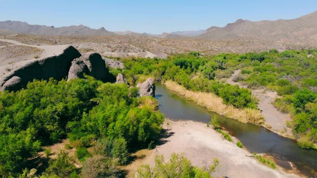 Aerial view Bushes and dry grass in the mountainous terrain of the Utah desert. Docile climate and greenery growing near the river. An oasis in the desert.