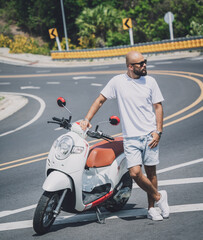 Fototapeta na wymiar Stylish young man with his motorbike on the road