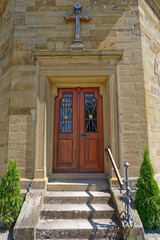 Come in, entrance of a mountain chapel with beautiful wooden door and wrought iron grille.