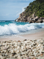 Scenic view of Sai Daeng Beach, Koh Tao Island tropical paradise. White sand beach with wave splash and rocky coastline. Surat Thani, Thailand. Selective focus, blurred coral beach foreground.