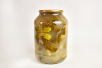 A glass jar with canned cucumbers on a white background.