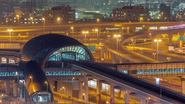 Futuristic building of Dubai metro station and big junction behind in Dubai Marina aerial night timelapse. Traffic on Sheikh Zayed road highway, United Arab Emirates
