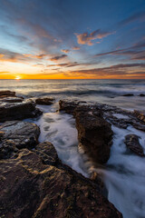 Beautiful sunrise view at rocky beach shore.