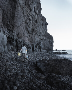 fisherman walking along a stone beach on the island of gran canaria