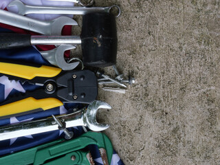 Happy Labor day concept. America flag with different construction tools on concrete background, copy space for text area.