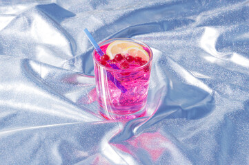 Pink fruity coctail drink with lemon and berries on a silver background. Summer futuristic concept.