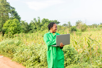 black Female farm agronomist checking an agricultural field using laptop