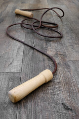 An old leather skipping rope with wooden handles on a wooden floor