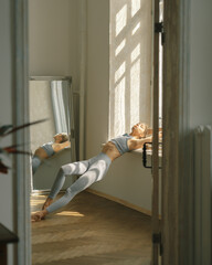Fitness, yoga, stretching and healthy lifestyle concept - young woman doing exercises near window at home