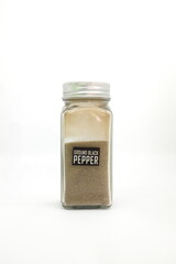 Ground black pepper powder in spice condiment glass bottle with label isolated in white background.
