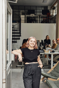 Portrait of smiling businesswoman standing by door at tech start-up office