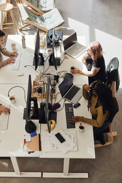 High angle view of computer programmers working while sitting at desk in tech start-up office