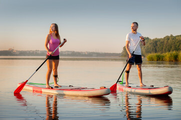 A couple swims together on a stand-up paddleboard, active lovers' recreation, water tourism and double skating