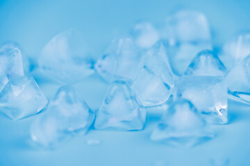 Ice cubes and water drops scattered on blue background