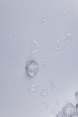 Ice cubes and water drops scattered on white background