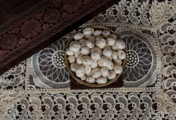 Crispy Lotus pops Seeds or Phool Makhana or Fox Nuts popular dry snacks from India served in a brass bowl. Top view. Makhana from Mithila region of Bihar in India. Mithilanchal. selective focus
