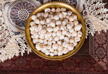 Crispy Lotus pops Seeds or Phool Makhana or Fox Nuts popular dry snacks from India served in a brass plate. Top view. Makhana from Mithila region of Bihar in India. Mithilanchal. selective focus