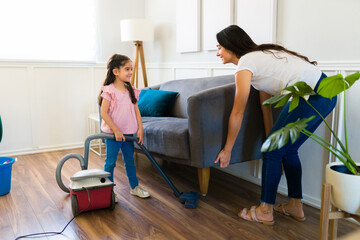 Beautiful mom and child vacuuming the living room and doing chores